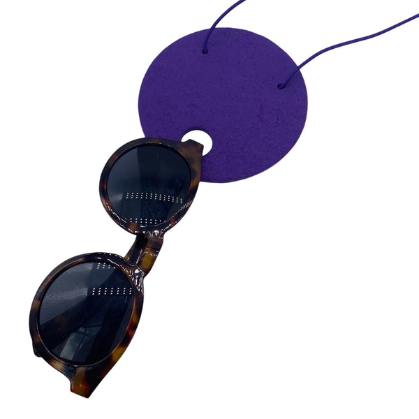 Large Purple Polymer Clay Statement necklace holding sunglasses on a white background