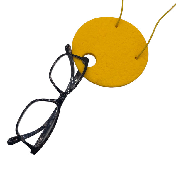 Large yellow Polymer Clay Statement necklace holding glasses on a white background