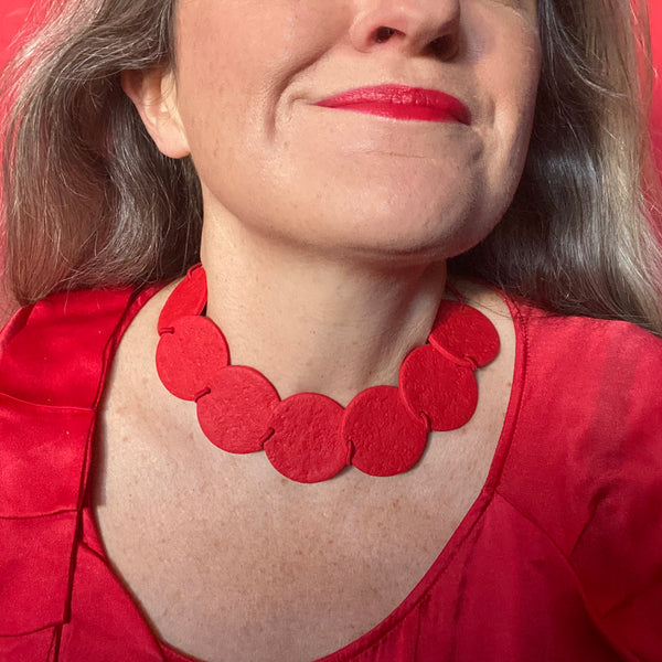 Someone wearing a Red polymer clay statement necklace with coordinating red elastic cord